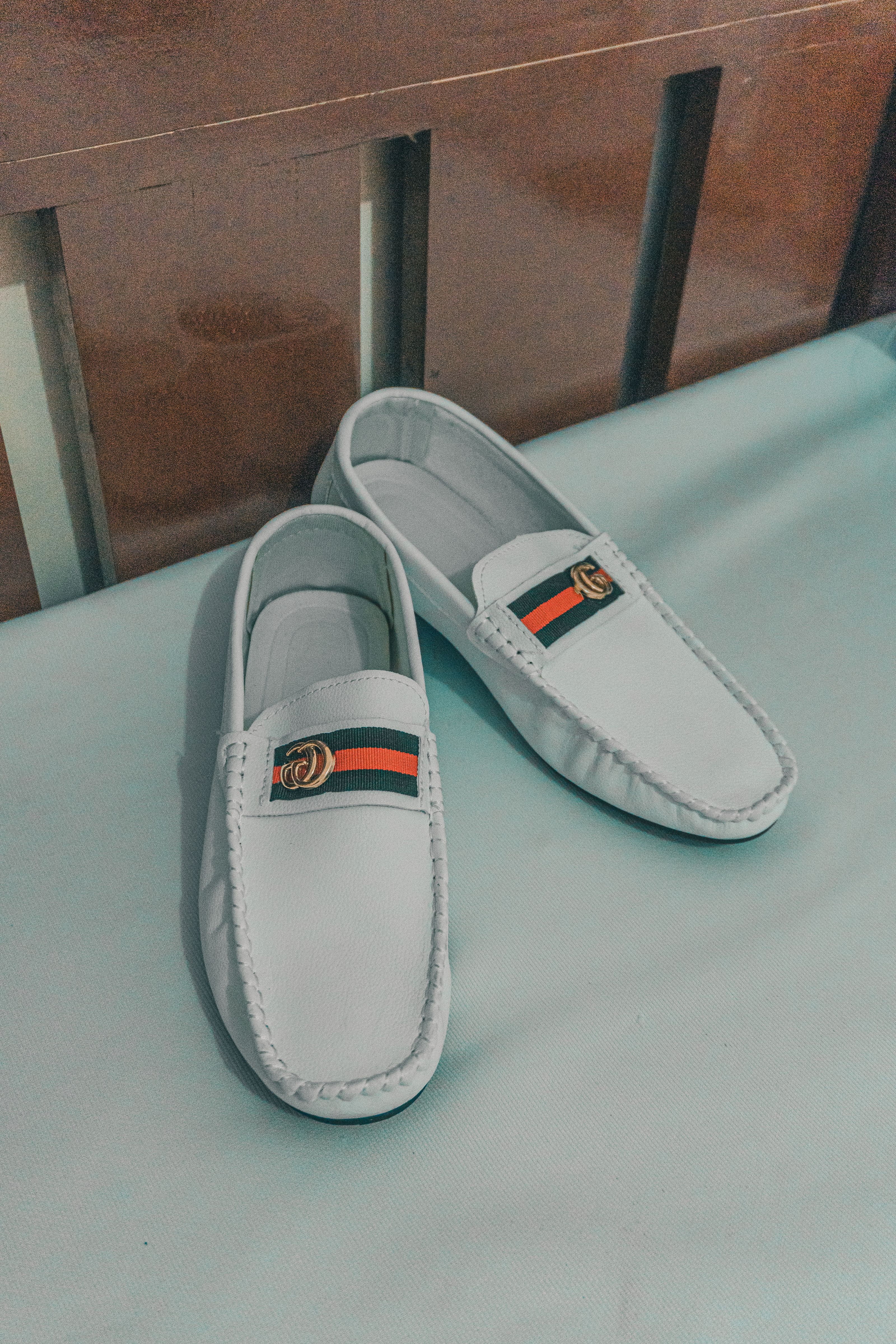 Close-up de elegantes mocassins de couro branco com um logo de designer em uma cama.