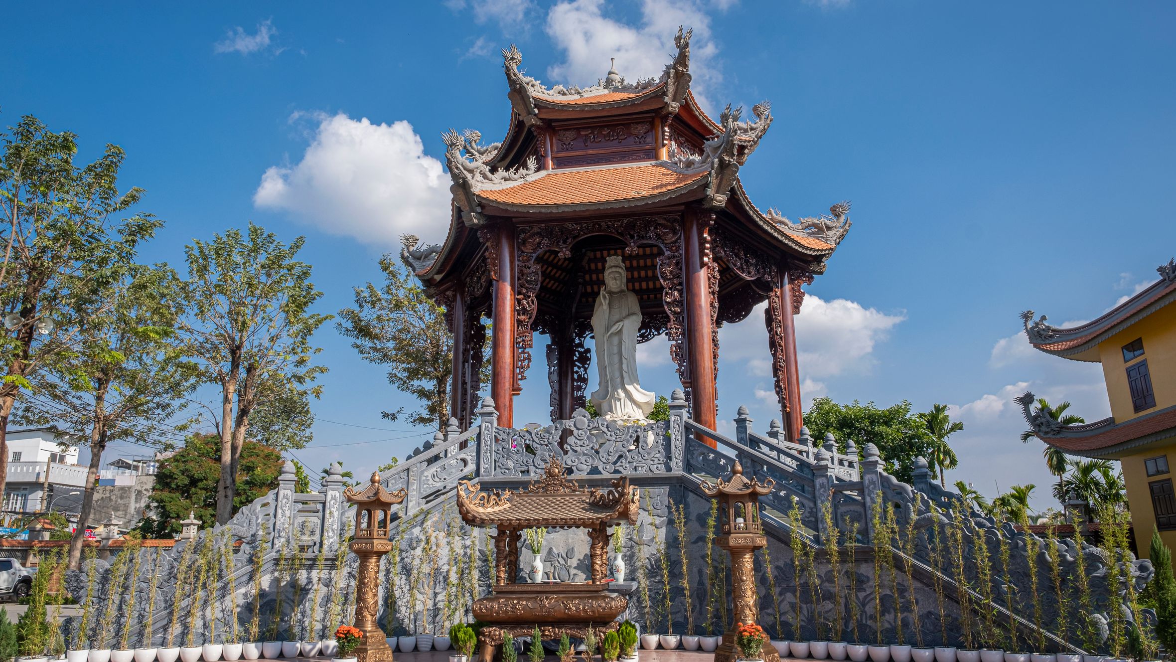Traditional Buddhist shrine with intricate sculpture in Ho Chi Minh City, showcasing Vietnamese architecture under a blue sky.