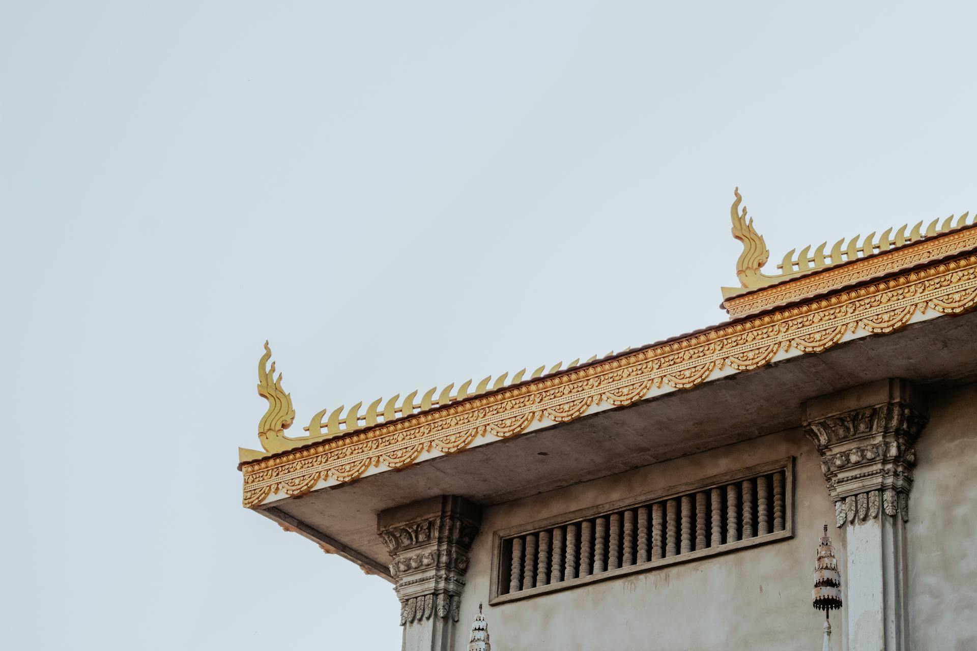 Detailed view of a traditional Cambodian temple roof with ornate carvings and golden decorations.