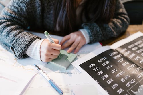 A Close-Up Shot of a Person Writing on a Sticky Note