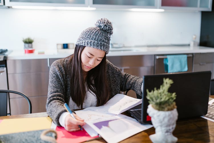 Woman In Hat Working With Statistical Data At Home Office