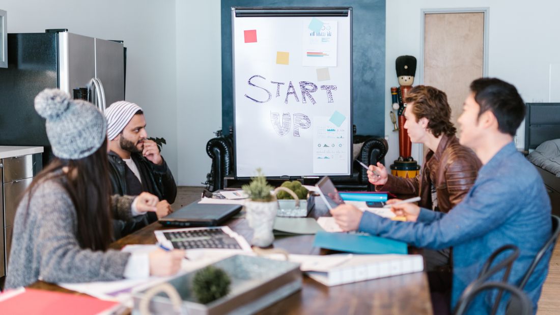 Equipo diverso trabajando alrededor de una mesa en una oficina startup, planificando y discutiendo ideas