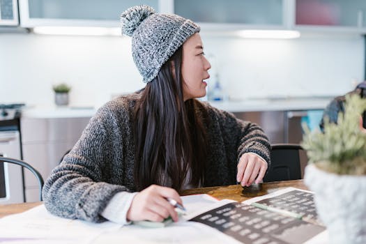 Woman in a cozy office setting, reviewing documents and taking notes at a table.