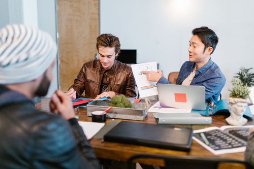 Free Team discussing project ideas in a modern office, focusing on documents and collaboration. Stock Photo
