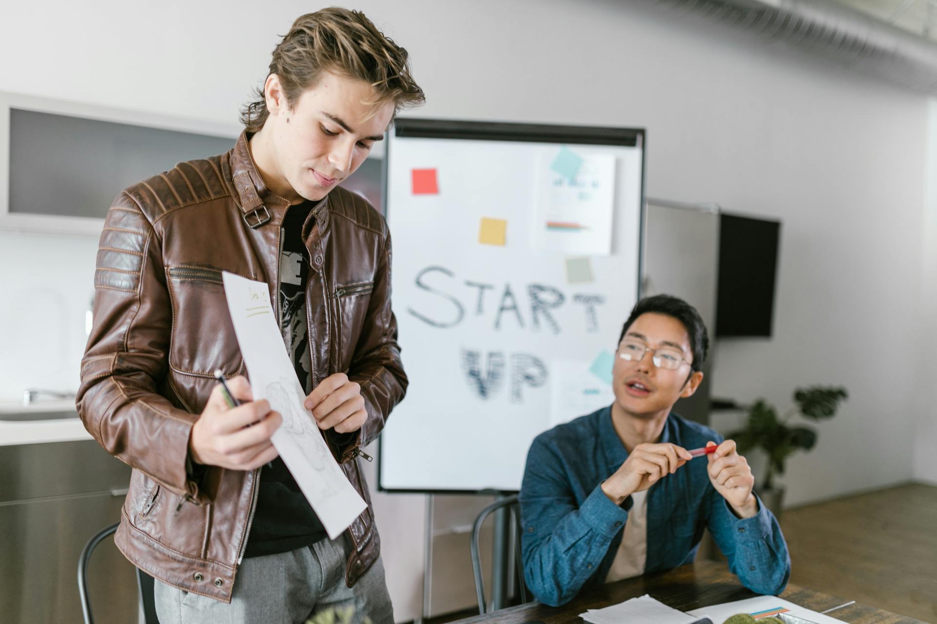 Two young men collaborating in a startup meeting with brainstorming session.