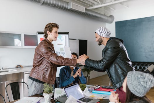 Two men shaking hands in a modern office setting, symbolizing a successful business agreement.
