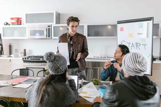 Young professionals discussing ideas around a table in a stylish office space, emphasizing teamwork and innovation.