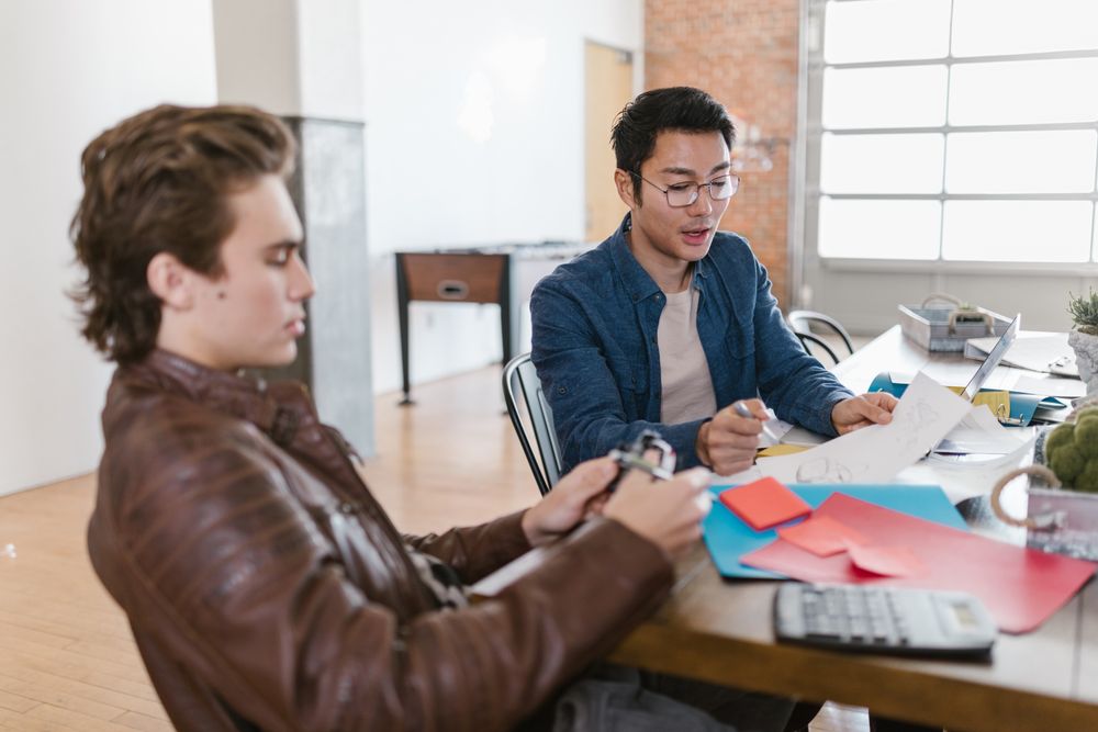 Two young entrepreneurs brainstorming ideas together in a modern startup office.