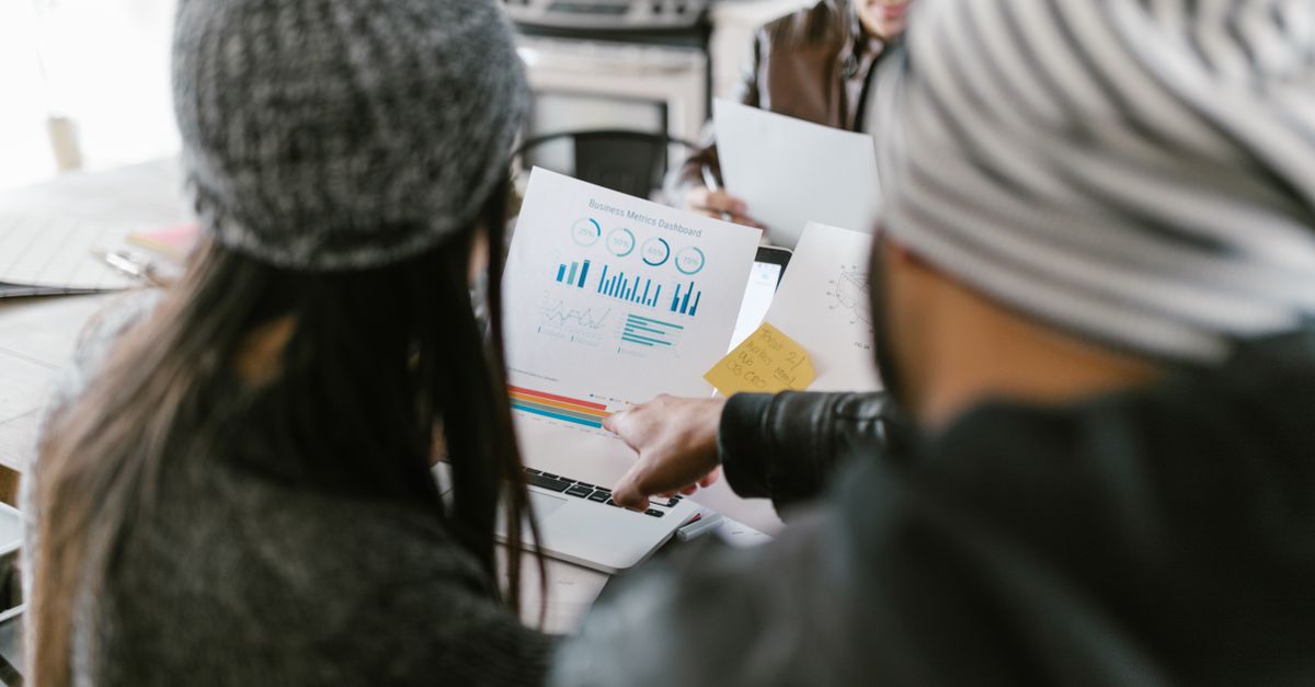 Team members discussing business metrics using printed charts in a cozy meeting space.