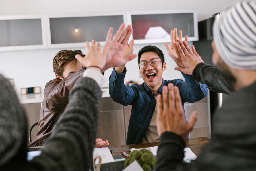 Diverse colleagues celebrating together with a joyful high five at the office