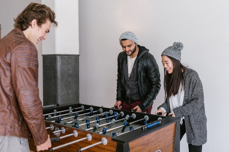 Multiracial Group Of People Playing Foosball