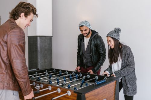 Free A diverse group of adults having fun playing foosball indoors, embracing recreation and smiles. Stock Photo