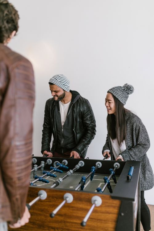 Free A diverse group of adults enjoying an indoor foosball game, having fun and smiling. Stock Photo