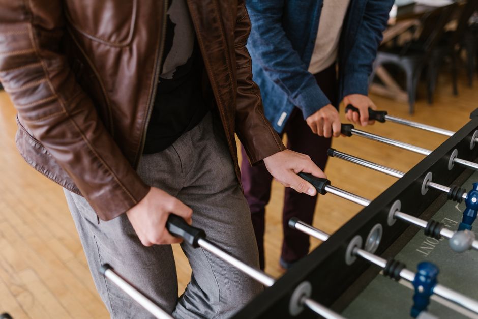 Adults engaged in a lively game of foosball indoors, capturing the essence of leisure and fun. Adults engaged in a lively game of foosball indoors, capturing the essence of leisure and fun.