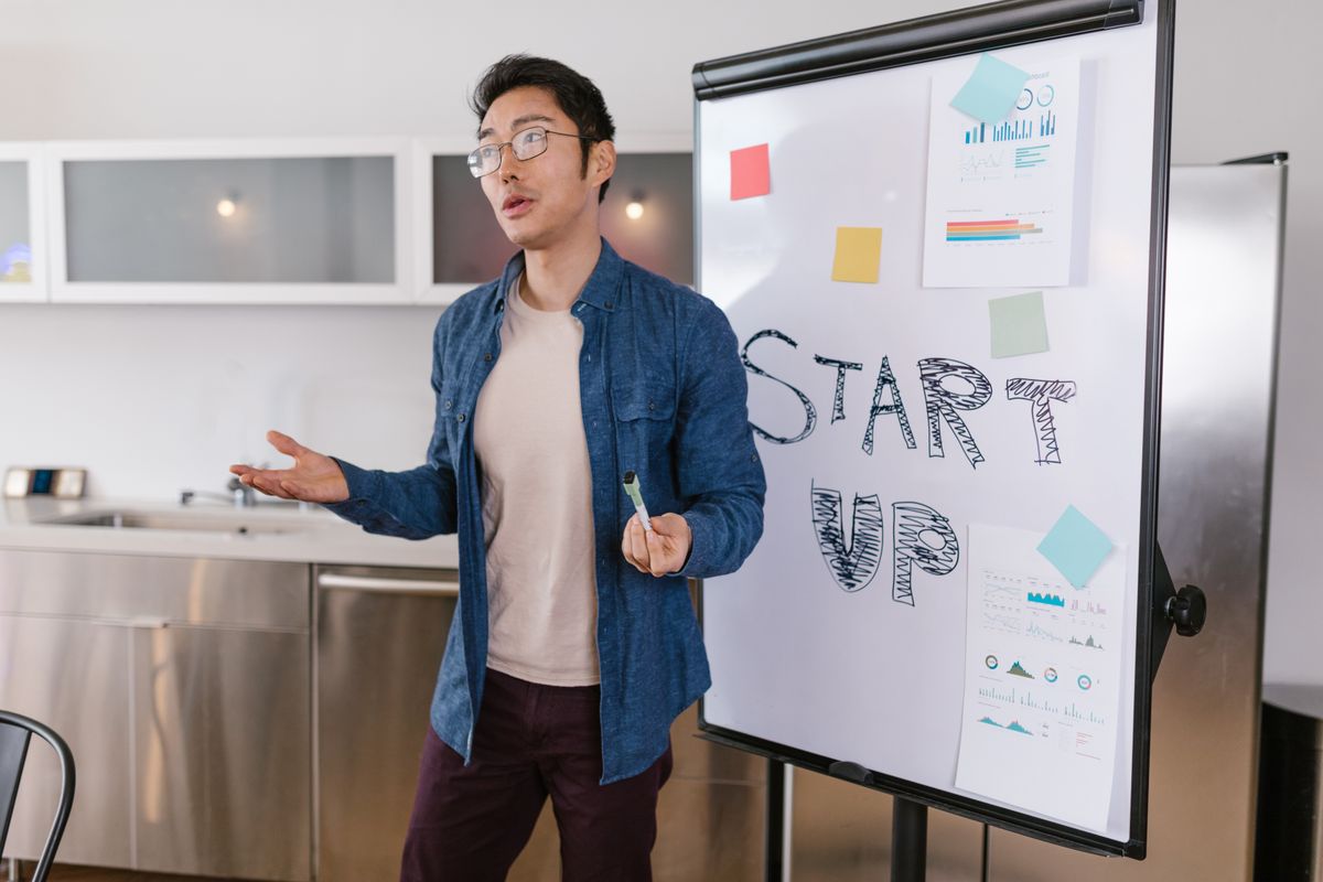 A founder presenting a startup idea with charts and graphs on a whiteboard