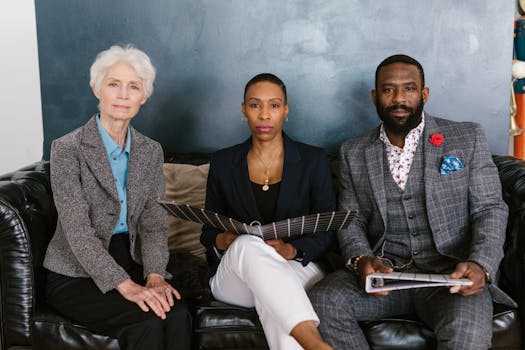 A diverse group of professionals sitting on a sofa in an office setting, showcasing teamwork and collaboration.