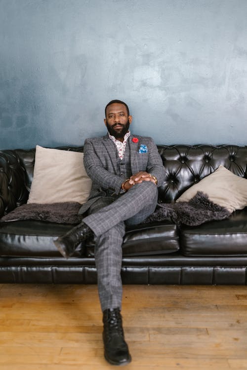 Man in Gray Suit Sitting on the Black Leather Couch