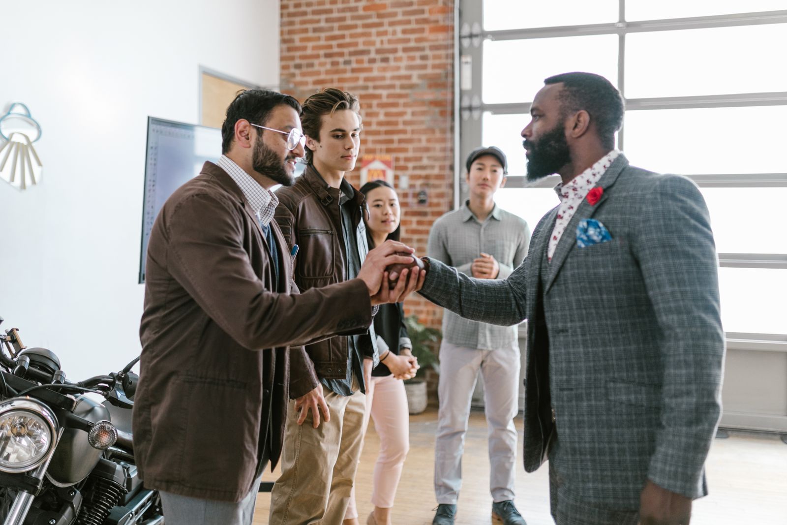 A larger group of business professionals greeting each other with a handshake in a modern office