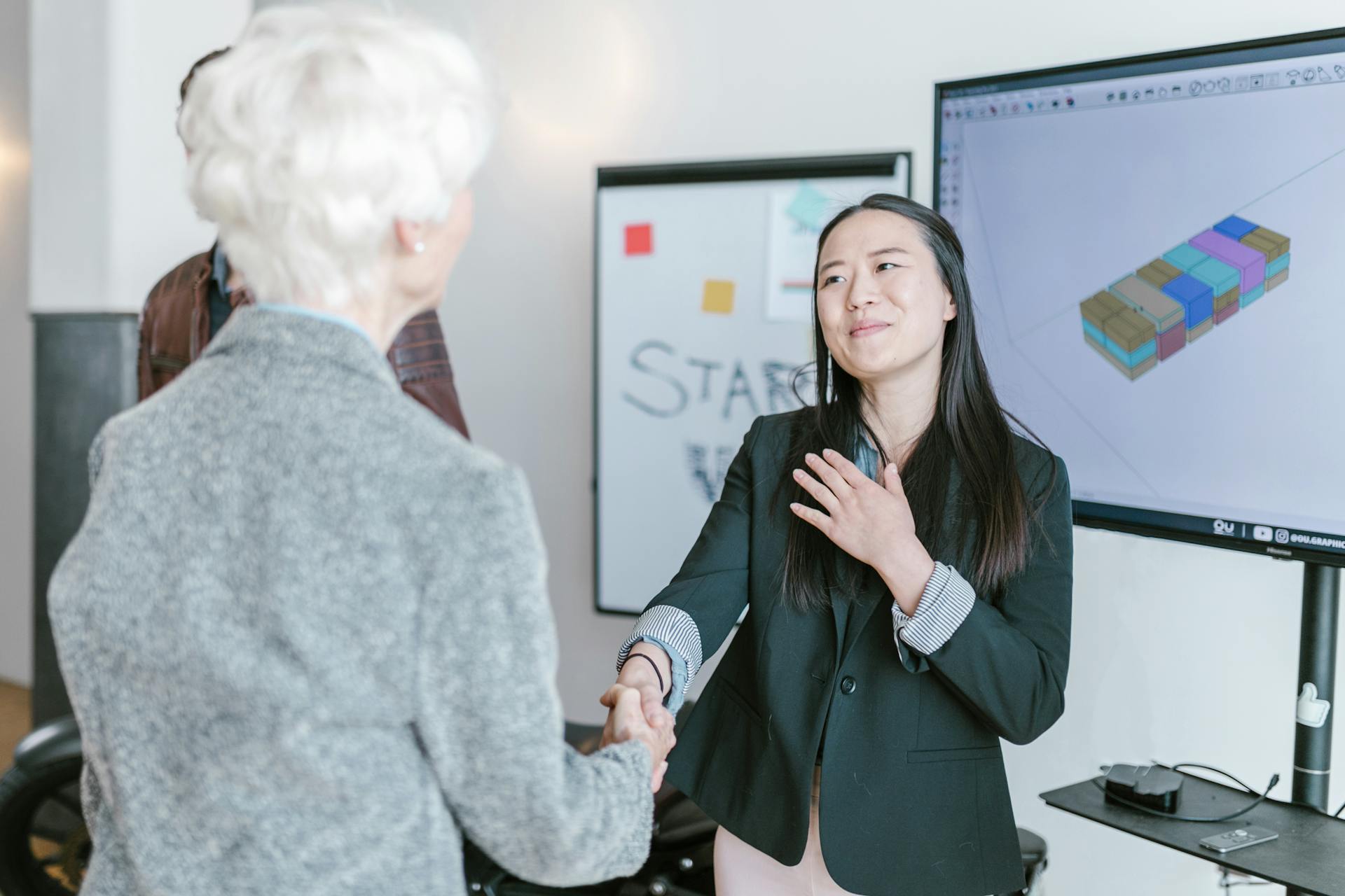 Professional women shaking hands in a corporate office setting, symbolizing a successful business agreement.