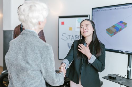 Free Professional women shaking hands in a corporate office setting, symbolizing a successful business agreement. Stock Photo