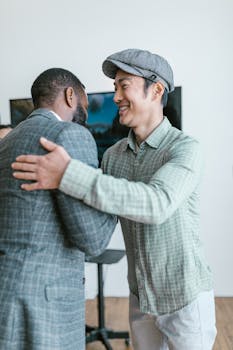 Two men in business attire exchanging a warm handshake in a modern office setting.
