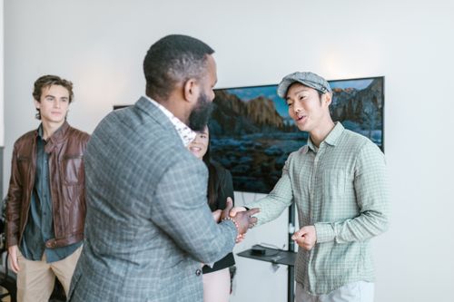 Free Diverse entrepreneurs engaging in a friendly handshake inside a modern office space. Stock Photo