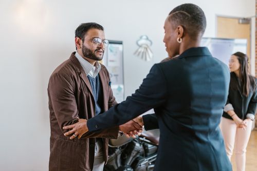 Free Business professionals greeting with a handshake in an office setting, promoting teamwork and cooperation. Stock Photo