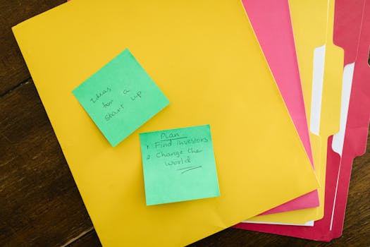 Startup ideas on sticky notes with colorful folders on a wooden surface, an inspiring organizational theme.
