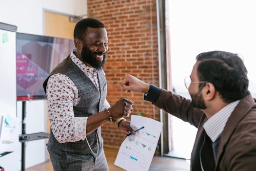 Two diverse businessmen share a fist bump at the office, symbolizing successful teamwork.