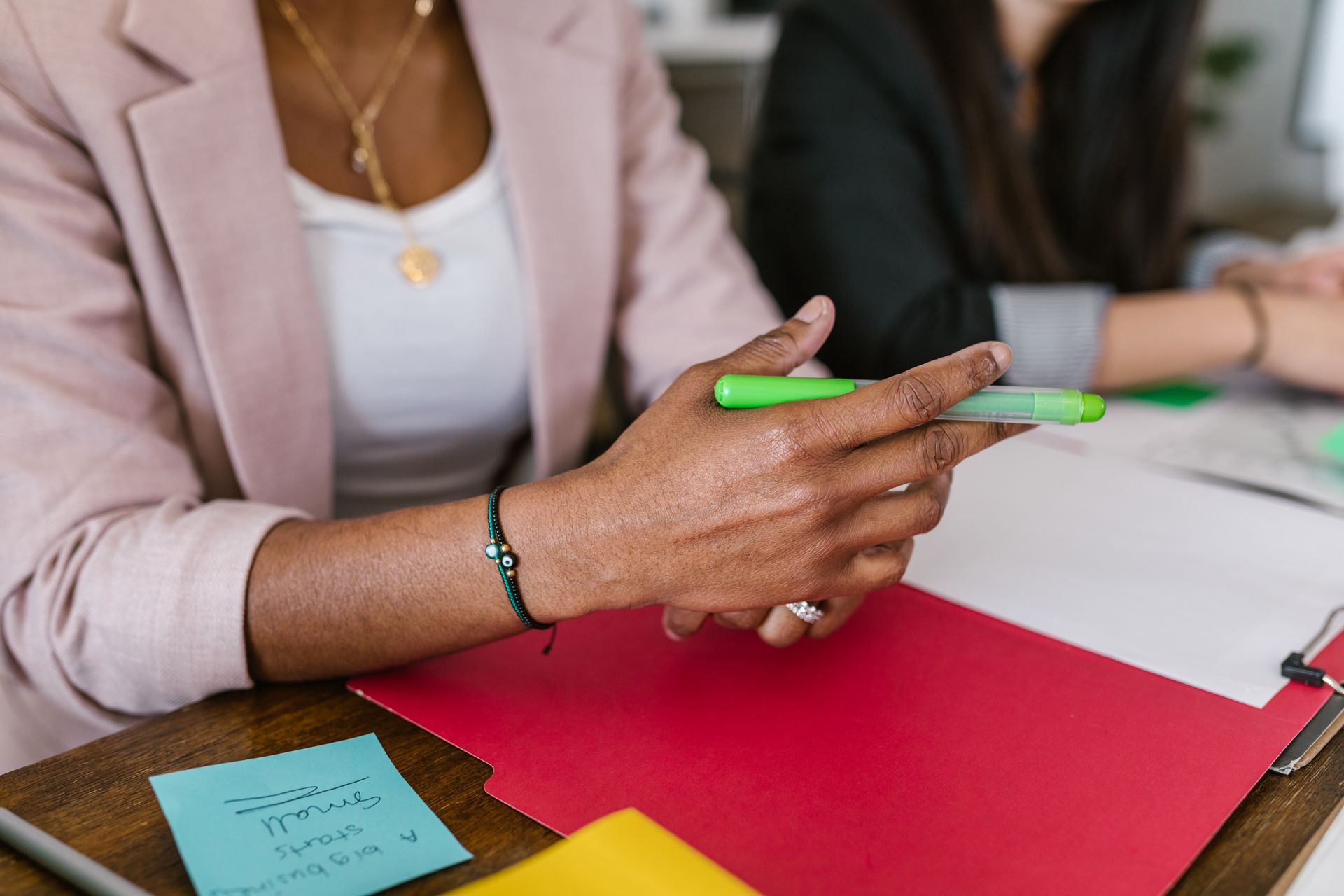 Professional setting with diverse hands holding pens during a business meeting.