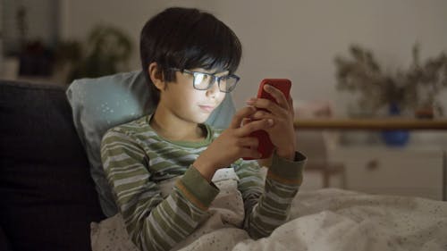 Free Boy in Striped Long Sleeves Using a Smartphone Stock Photo