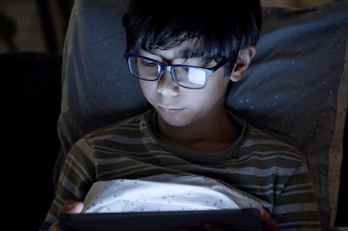 Free Boy Wearing Eyeglasses Using a Digital Tablet Stock Photo