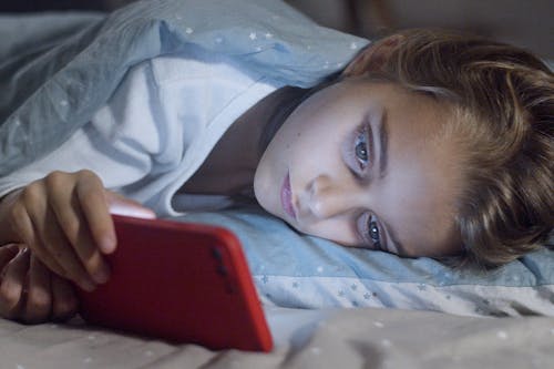 Free Girl Using her Phone in Bed Stock Photo