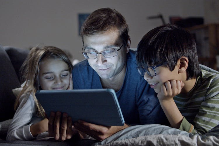 A Man And His Children Looking At A Tablet