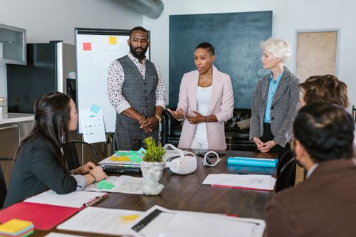 Free A diverse team collaborates in a modern office setting, discussing strategies and teamwork. Stock Photo