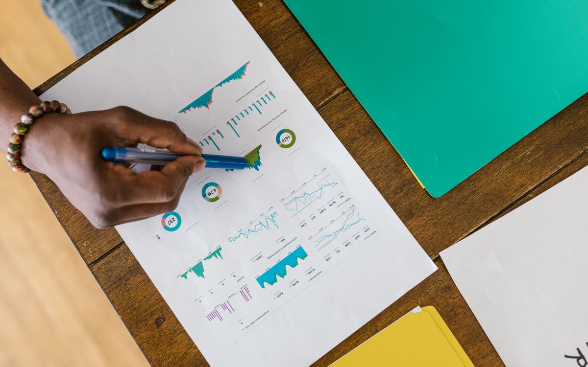Overhead view of a person analyzing business charts and graphs on paper.