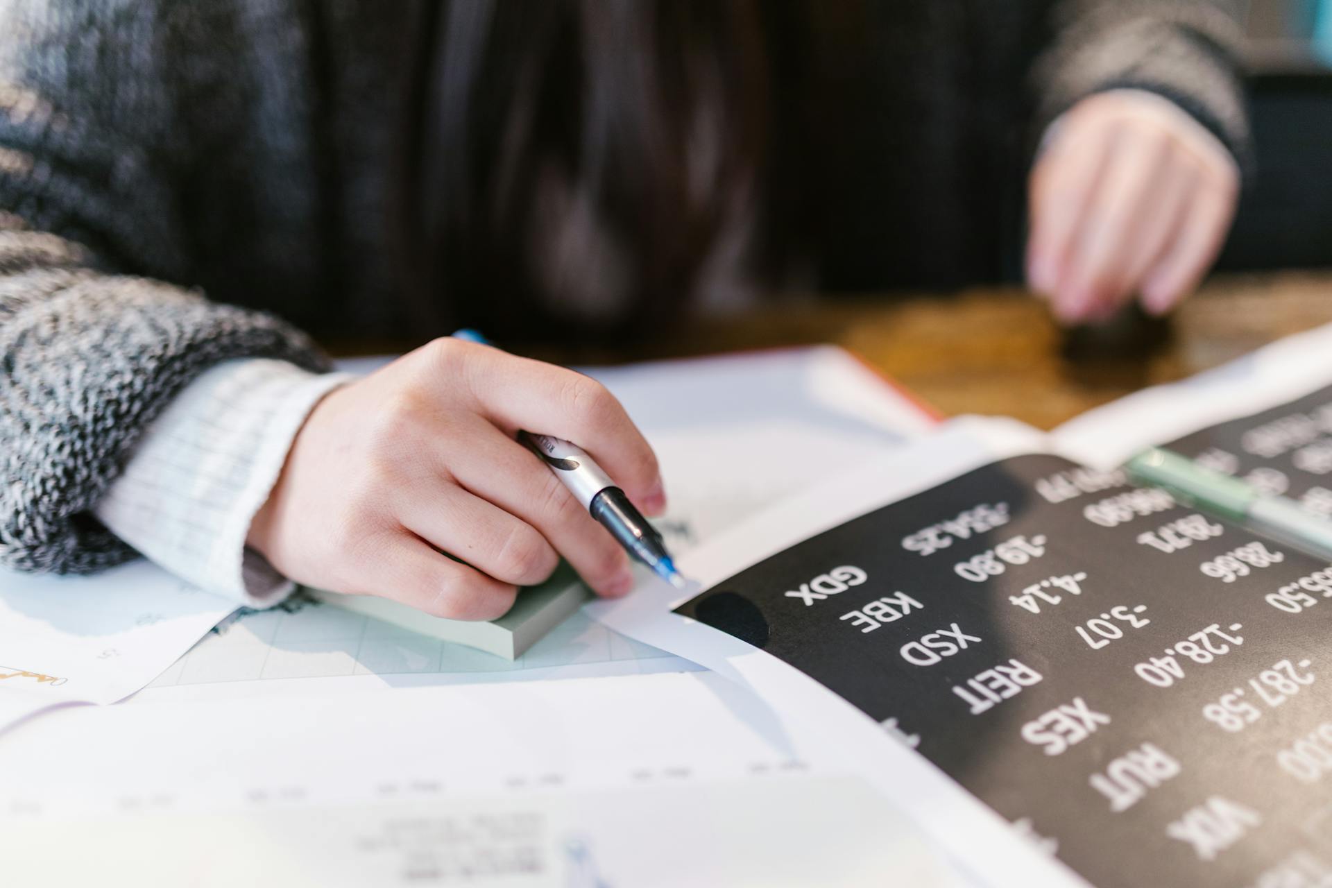 Close-up of a woman reviewing financial documents with focus on numbers and calculations.