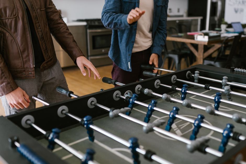 Two friends enjoying a game of foosball indoors, showcasing fun and bonding time.