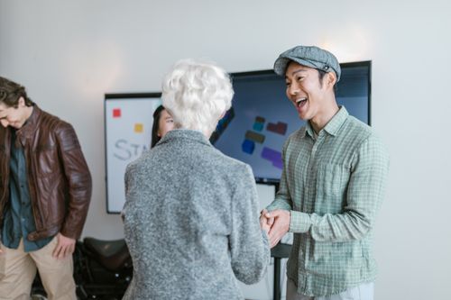Free Asian man and elderly woman in a business meeting shaking hands, conveying collaboration and agreement. Stock Photo