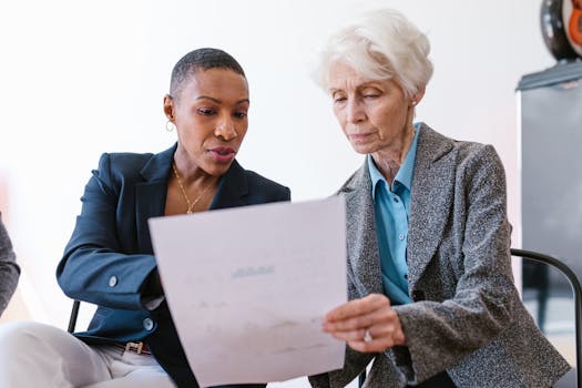 Two professional women discussing a document in an office setting.