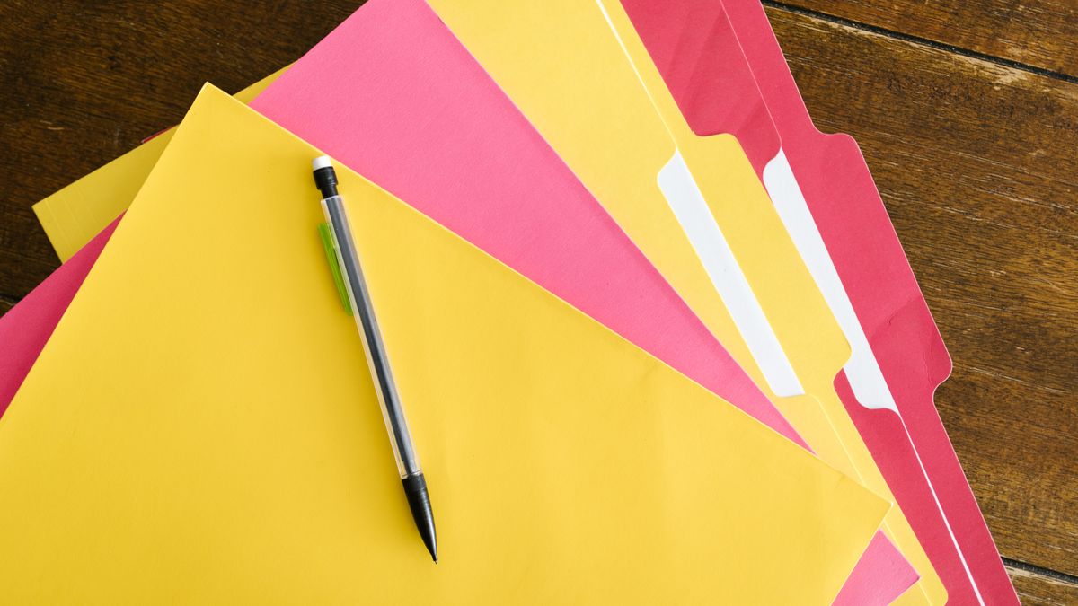 Colorful folders and pen arranged on a wooden table for office organization.