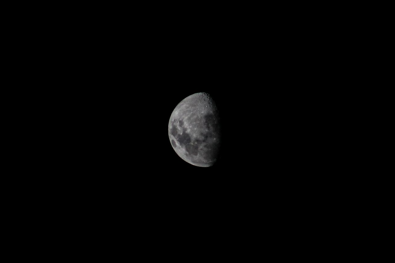 detailed shot of the half moon against a stark black night sky capturi