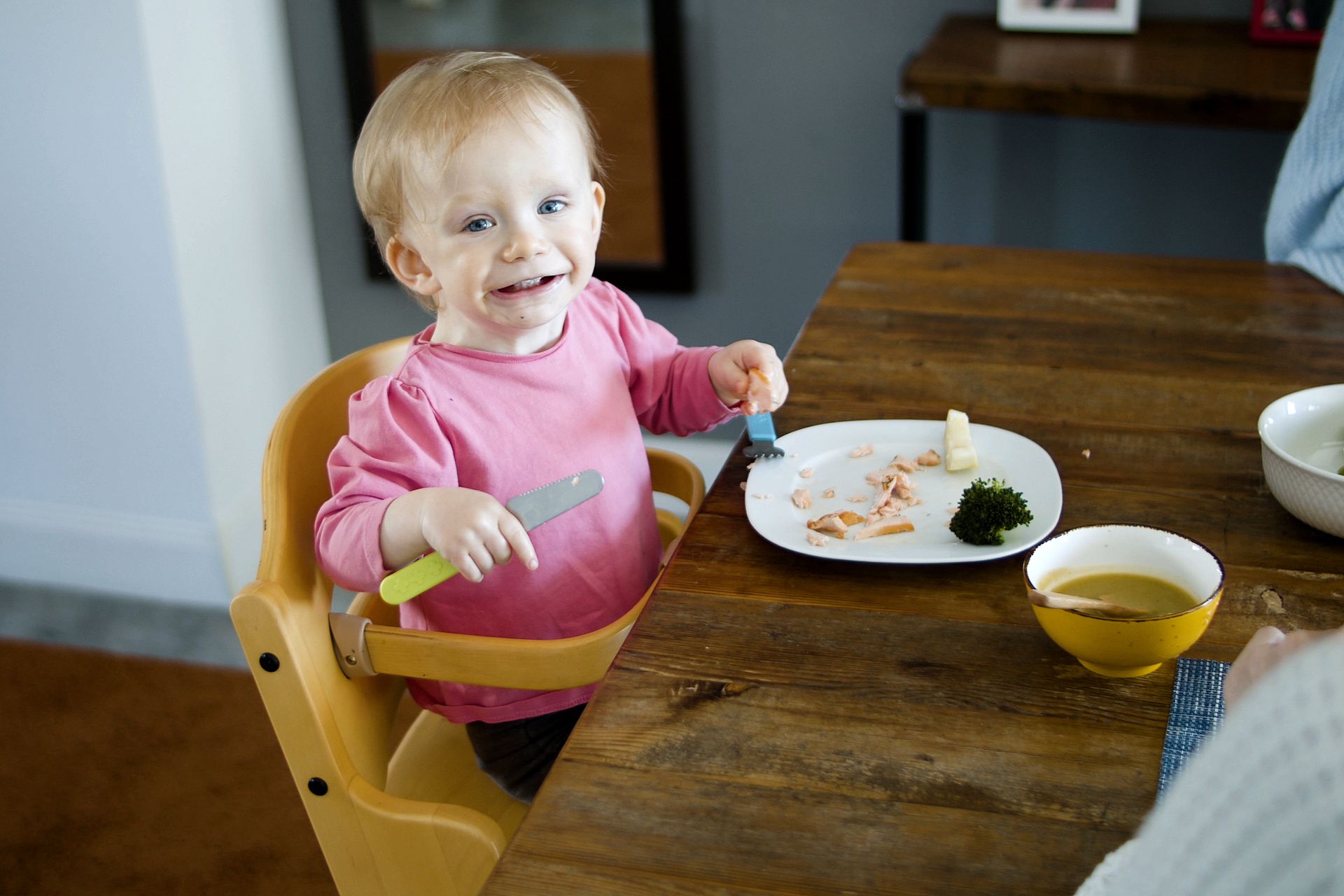 A Child on a High Chair Eating Breakfast