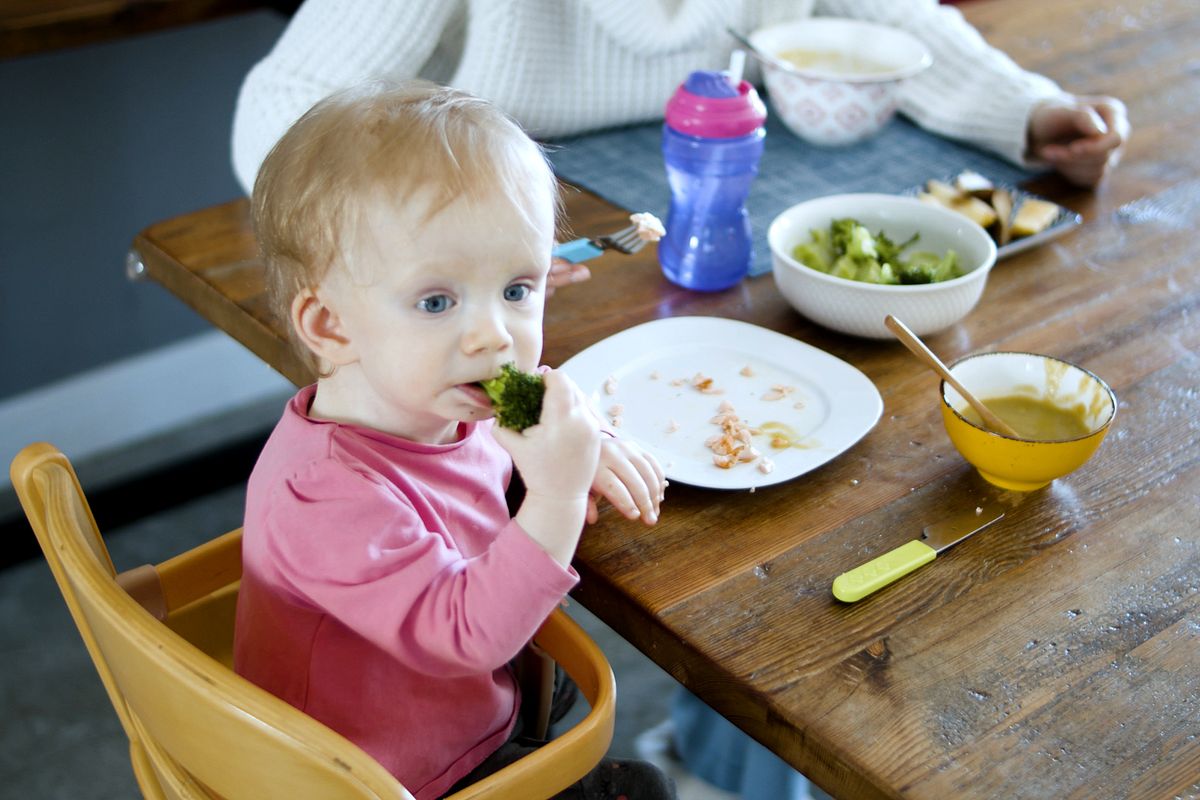 Toddler in a high chair tasting vegetables