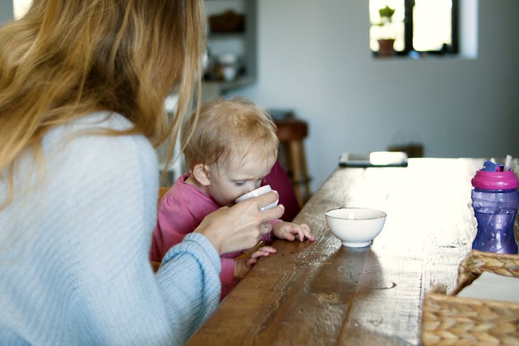 Mother Giving Drink To A Baby In Pink Long Sleeve Shirt