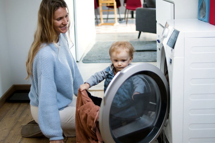 A Woman And Baby Girl Looking The Washing Machine 