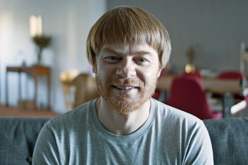 Free Friendly bearded man smiling indoors in a cozy setting. Stock Photo