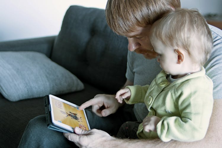 Father And Child Sitting On Gray Couch