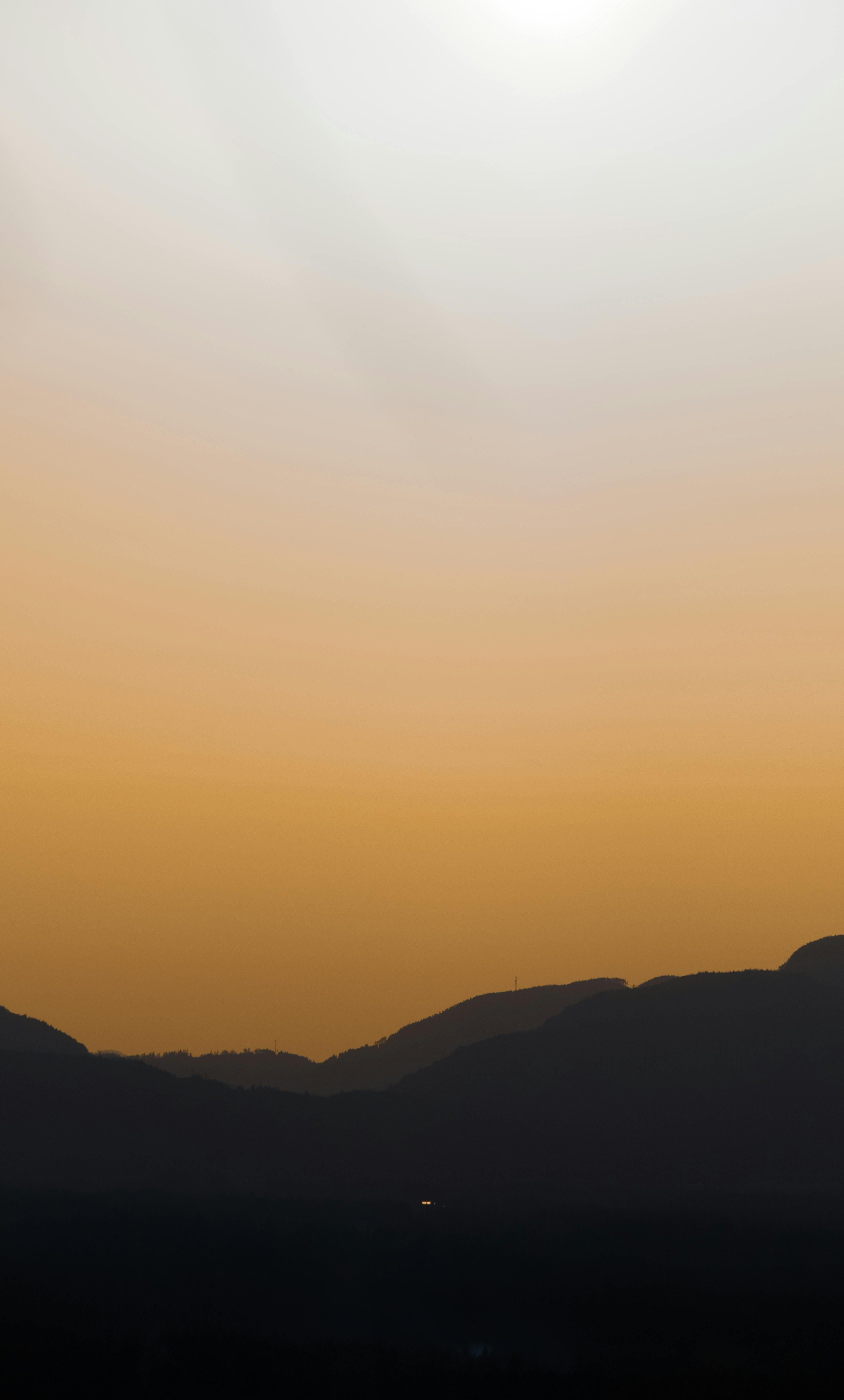 A dramatic sunset casting orange hues over silhouettes of mountains in British Columbia, Canada.