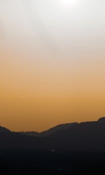 A dramatic sunset casting orange hues over silhouettes of mountains in British Columbia, Canada.